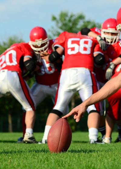 Holder holding football for field goal kicker
